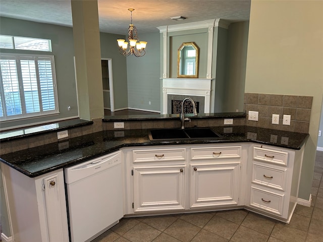 kitchen featuring white cabinets, dishwasher, backsplash, dark stone countertops, and a sink