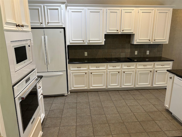 kitchen with tile patterned flooring, white appliances, white cabinetry, tasteful backsplash, and dark stone countertops