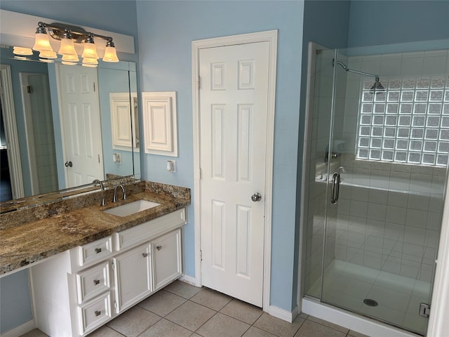 bathroom featuring a shower stall, vanity, baseboards, and tile patterned floors