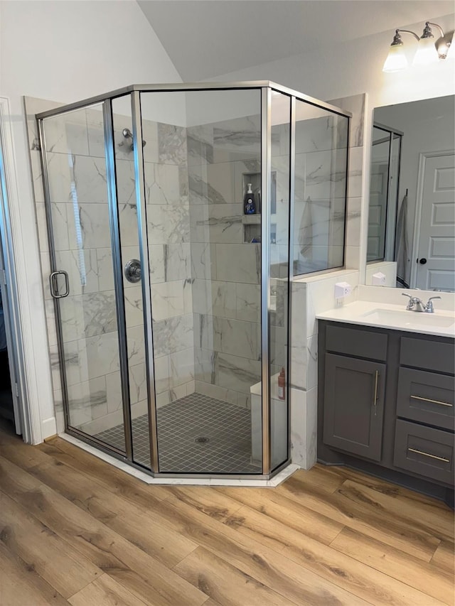 full bath with a shower stall, wood finished floors, and vanity