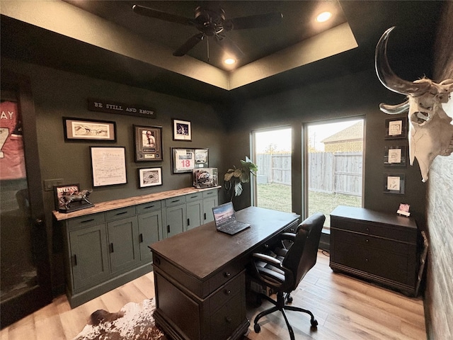 office area featuring light wood-type flooring, a raised ceiling, a ceiling fan, and recessed lighting