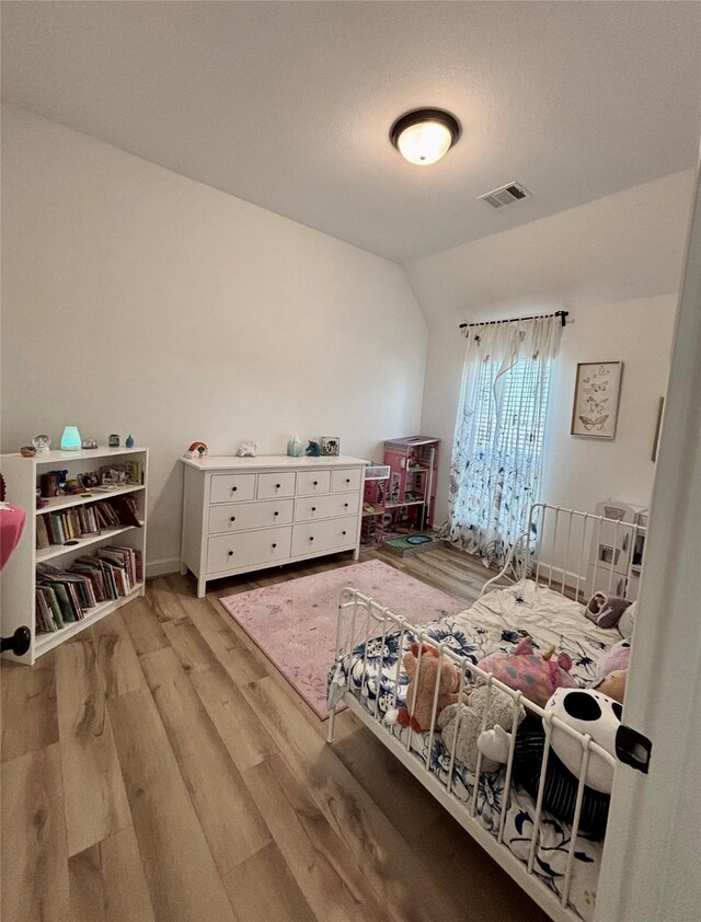 bedroom featuring lofted ceiling, light wood finished floors, and visible vents