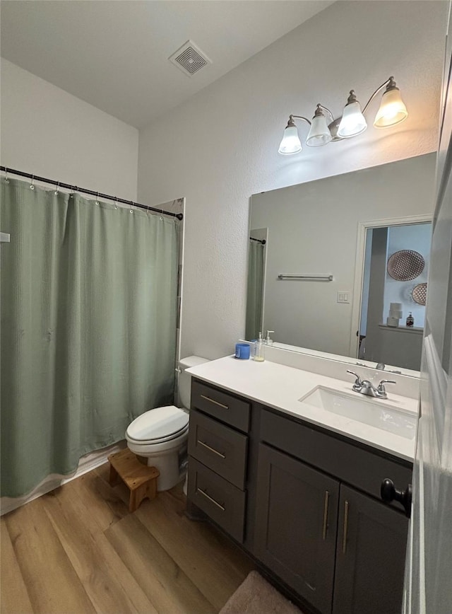 bathroom with curtained shower, visible vents, toilet, vanity, and wood finished floors