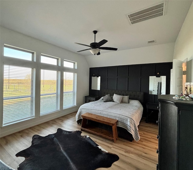 bedroom featuring light wood-style floors, lofted ceiling, and visible vents