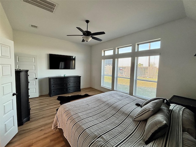 bedroom featuring baseboards, ceiling fan, visible vents, and wood finished floors