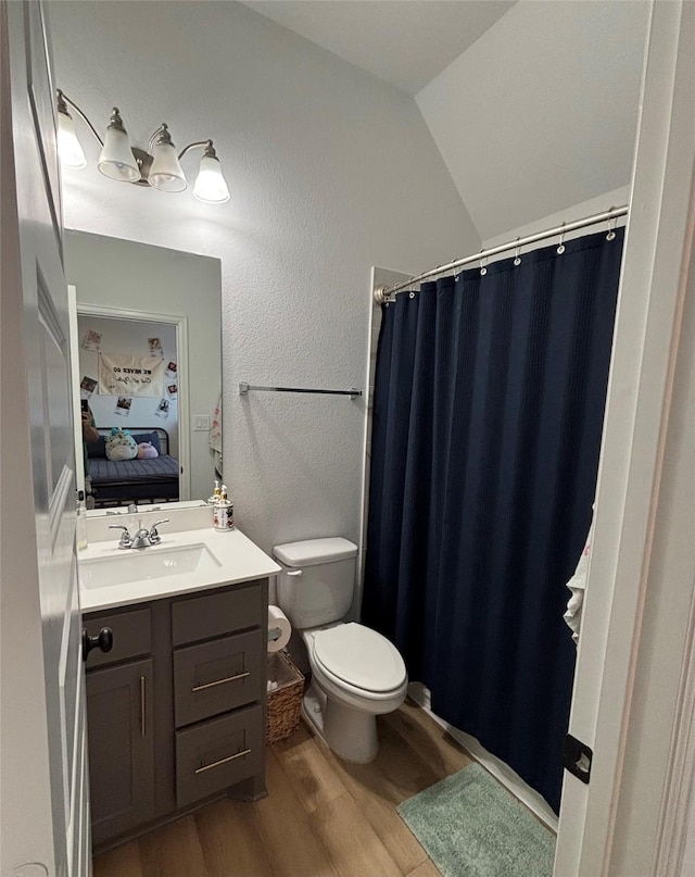 bathroom featuring ensuite bathroom, a textured wall, toilet, wood finished floors, and vanity