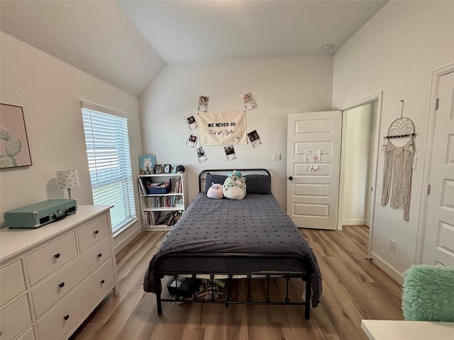 bedroom with light wood-style flooring, baseboards, and vaulted ceiling