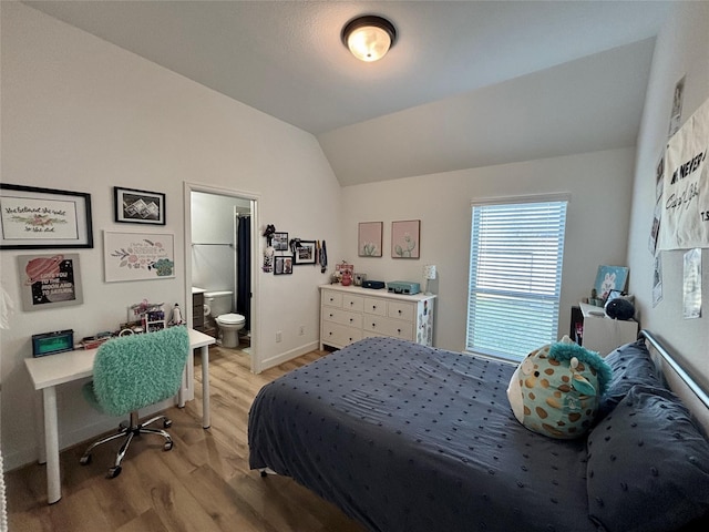 bedroom with vaulted ceiling, ensuite bathroom, light wood-style flooring, and baseboards