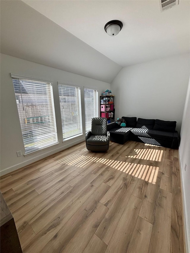 sitting room featuring visible vents, vaulted ceiling, baseboards, and wood finished floors