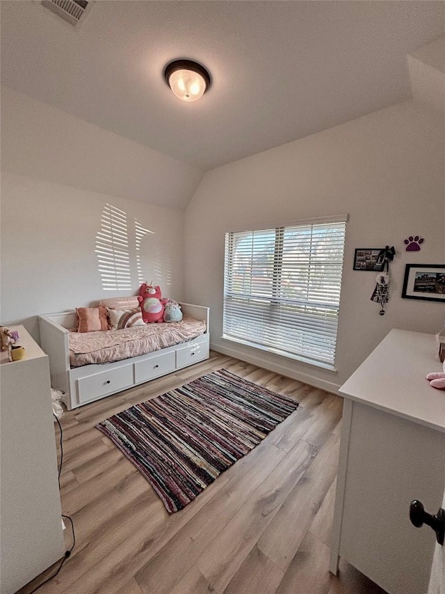 bedroom featuring light wood-style floors, visible vents, and vaulted ceiling