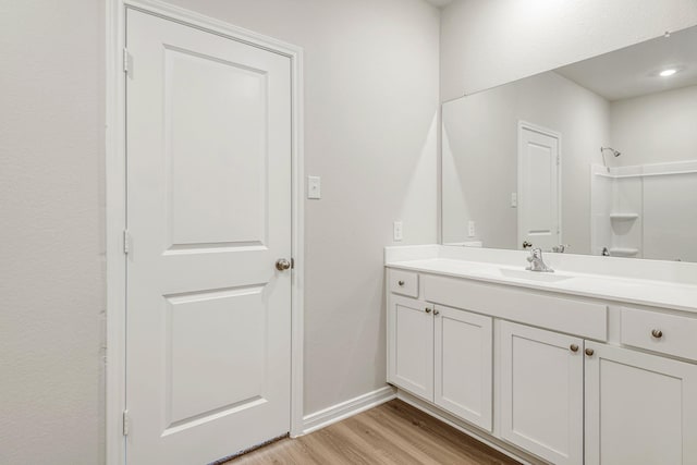 full bath featuring baseboards, walk in shower, wood finished floors, and vanity