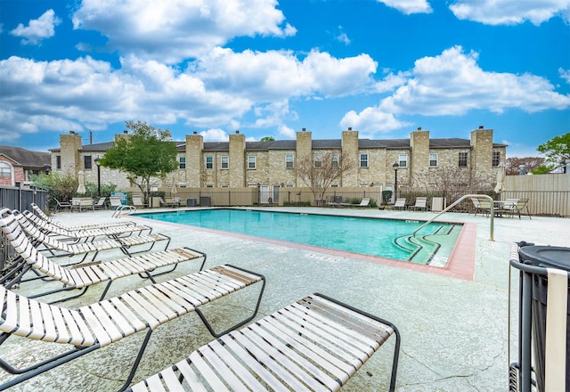 community pool with a patio area and fence