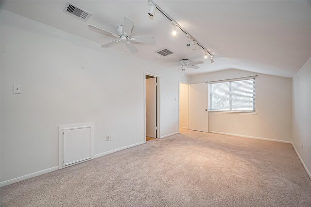 spare room with visible vents, light colored carpet, baseboards, and vaulted ceiling