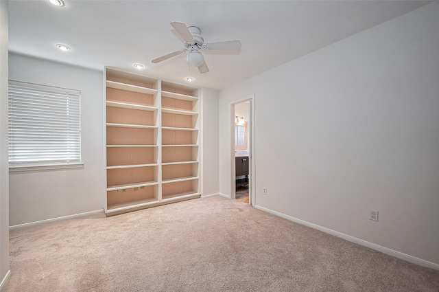 empty room with built in shelves, ceiling fan, baseboards, carpet floors, and recessed lighting