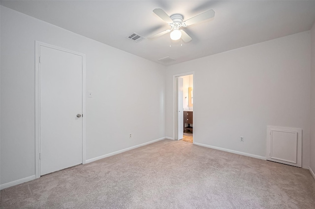 empty room featuring light carpet, visible vents, baseboards, and ceiling fan