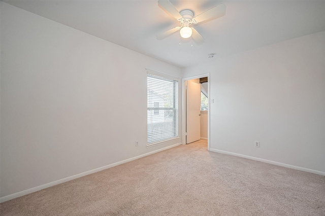 empty room featuring baseboards, light colored carpet, and a ceiling fan