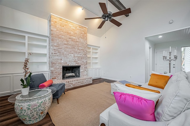 living area with a brick fireplace, built in features, wood finished floors, and high vaulted ceiling