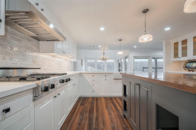 kitchen featuring dark wood-type flooring, stainless steel gas stovetop, white cabinets, glass insert cabinets, and under cabinet range hood