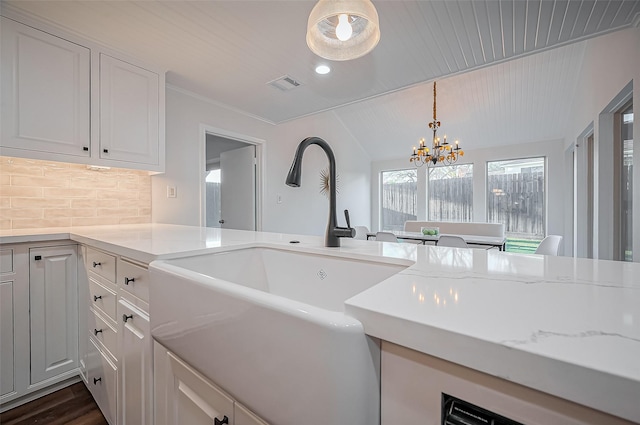 kitchen with visible vents, backsplash, white cabinetry, and a sink