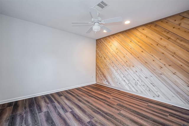 unfurnished room featuring wooden walls, wood finished floors, visible vents, baseboards, and recessed lighting