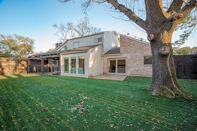 rear view of house with a yard, brick siding, and a fenced backyard