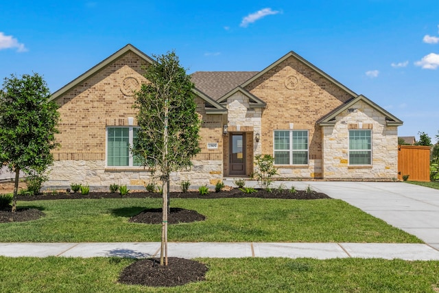 view of front of property featuring stone siding, a front lawn, and brick siding