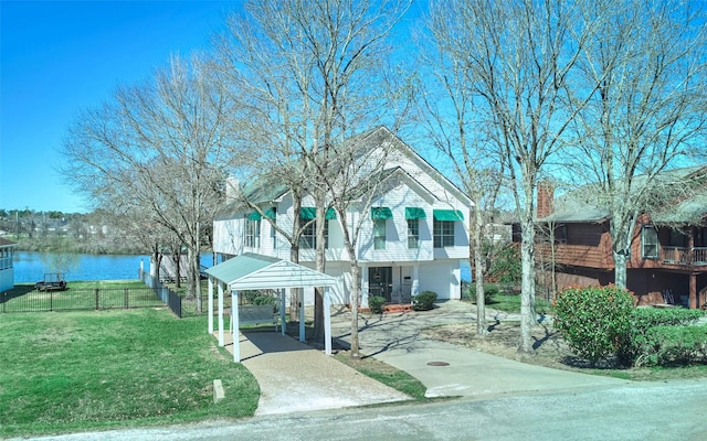 view of front of property with a front lawn, fence, a water view, concrete driveway, and a carport