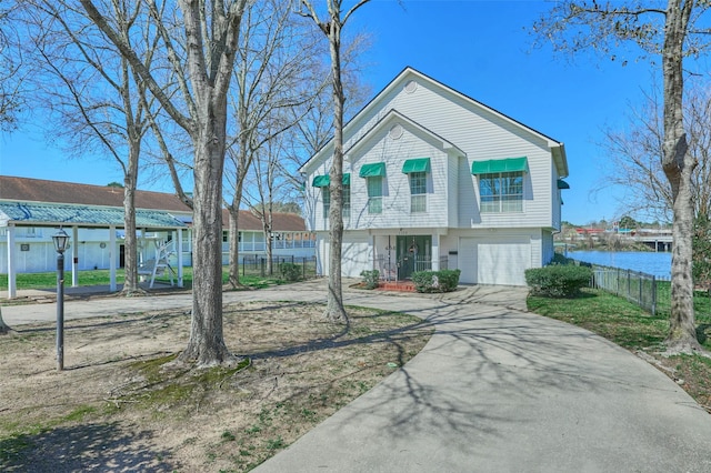 view of front of home with a water view, an attached garage, driveway, and fence