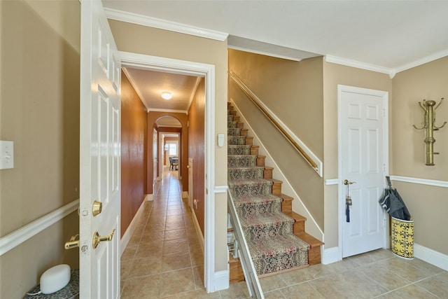 staircase featuring arched walkways, crown molding, and tile patterned flooring