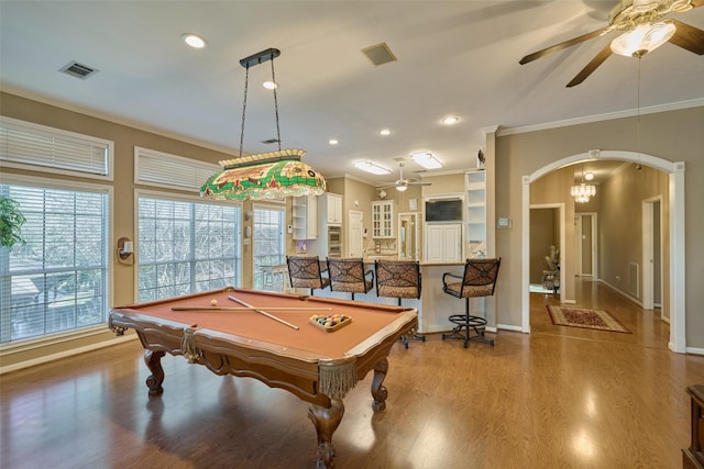 game room with visible vents, arched walkways, wood finished floors, and ornamental molding