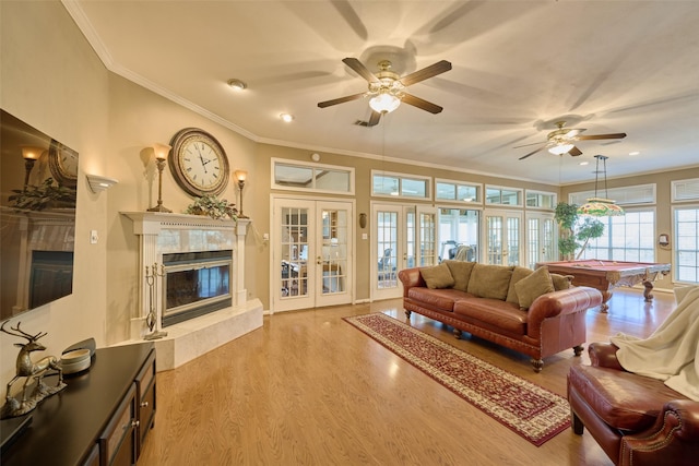 living area featuring billiards, wood finished floors, french doors, crown molding, and a premium fireplace