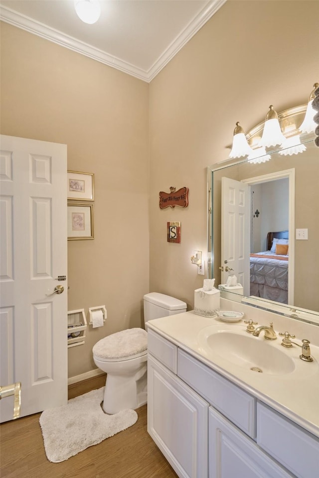 ensuite bathroom with connected bathroom, toilet, ornamental molding, wood finished floors, and vanity