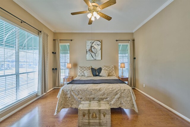 bedroom with ceiling fan, crown molding, baseboards, and wood finished floors