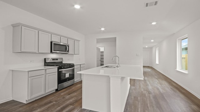 1658 Portia Ln, Conroe, TX 77301 - kitchen with stainless steel appliances, a sink, dark wood-style floors, a center island with sink, and light countertops