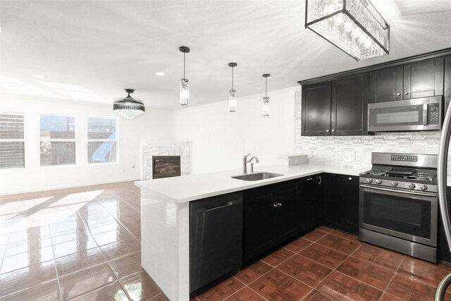 kitchen with a peninsula, a sink, stainless steel appliances, a fireplace, and backsplash