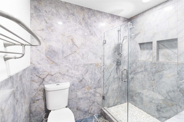 bathroom featuring a shower stall, toilet, and tile walls