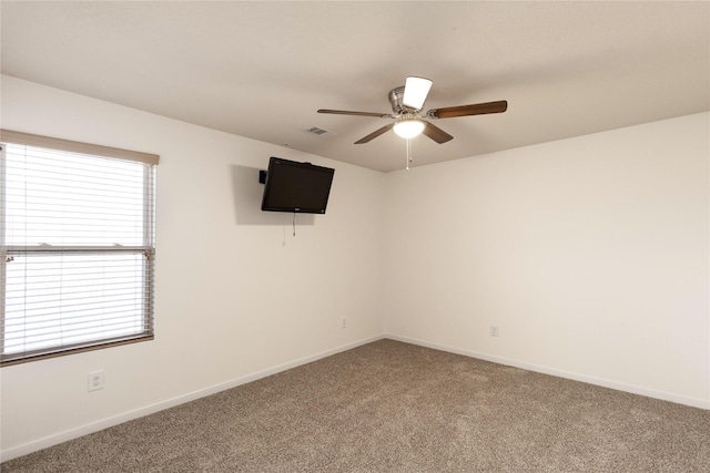 carpeted empty room with ceiling fan, visible vents, and baseboards