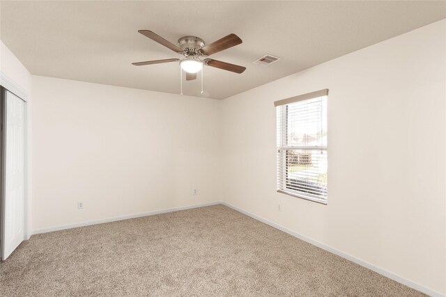 carpeted empty room featuring visible vents, ceiling fan, and baseboards