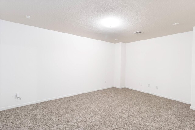 carpeted spare room featuring baseboards, visible vents, and a textured ceiling