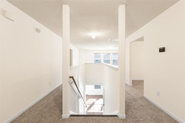 hall featuring baseboards, carpet flooring, and an upstairs landing