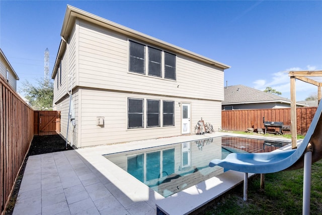 rear view of property with a patio area, a fenced backyard, a gate, and a fenced in pool