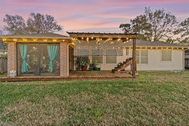 back of property with brick siding, a deck, and a lawn