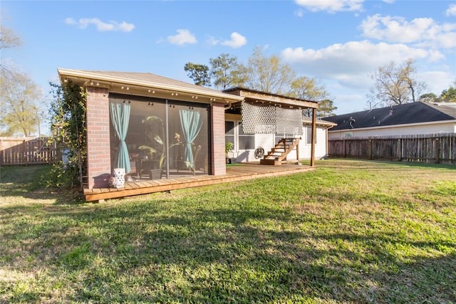 back of property with a yard, brick siding, a fenced backyard, and a sunroom