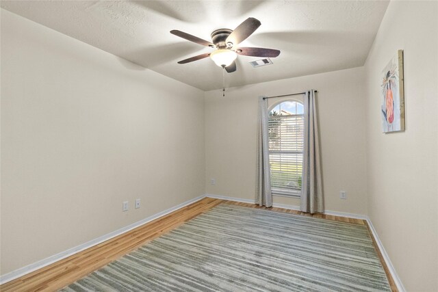 spare room with light wood-type flooring, visible vents, baseboards, and a ceiling fan