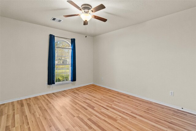 unfurnished room with light wood finished floors, visible vents, a ceiling fan, and baseboards