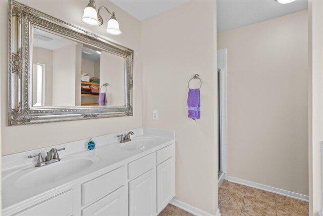 full bathroom featuring double vanity, an enclosed shower, baseboards, and a sink