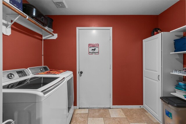 washroom with visible vents and washing machine and clothes dryer