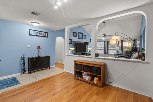 interior space with a ceiling fan, wood finished floors, visible vents, and arched walkways