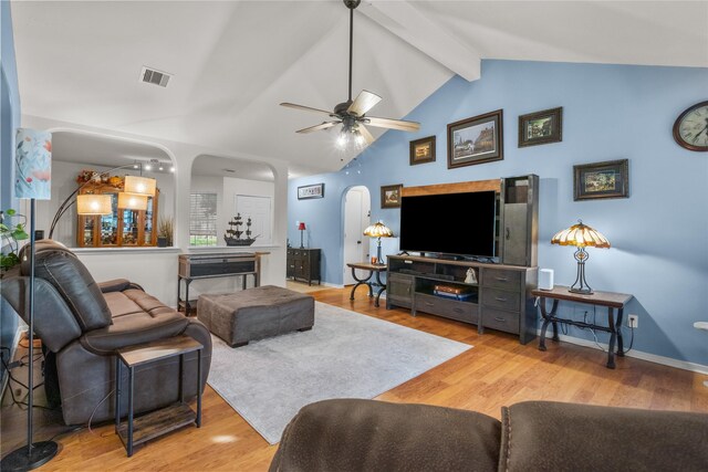 living area featuring visible vents, arched walkways, beam ceiling, and wood finished floors