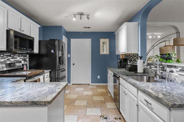 kitchen featuring light stone counters, white cabinets, appliances with stainless steel finishes, and a sink